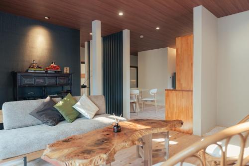 a living room with a couch and a wooden table at The Nature Uno 2026年リノベーション 直島好アクセス 古民家一棟貸切 最大4名2ldk平家 クイーンベッド2台 in Tamano