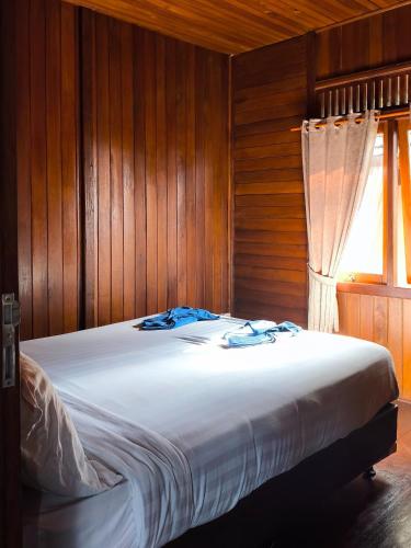 a bedroom with a bed with wooden walls and a window at D Royale Tapos Resort Bogor in Tapos