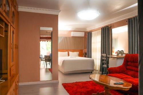 a hotel room with a bed and a red chair at Mamli Guestlodge & Conferencing in Schoemansdal