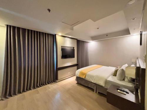 a hotel room with a bed and a flat screen tv at The Residences at BCCT in Manila