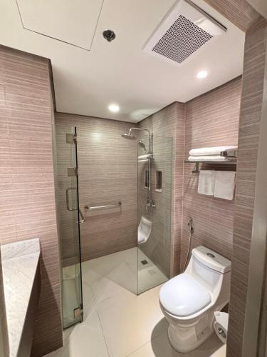a bathroom with a toilet and a glass shower at The Residences at BCCT in Manila