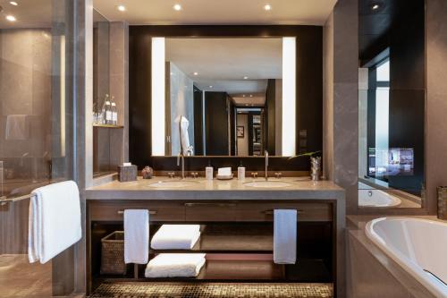 a bathroom with two sinks and a tub and a large mirror at Rosewood Phnom Penh in Phnom Penh
