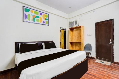 a bedroom with a large bed and a chair at Hotel O George Town in Colonelganj
