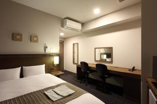 a hotel room with a bed and a desk at Toyooka Green Hotel Morris in Toyooka