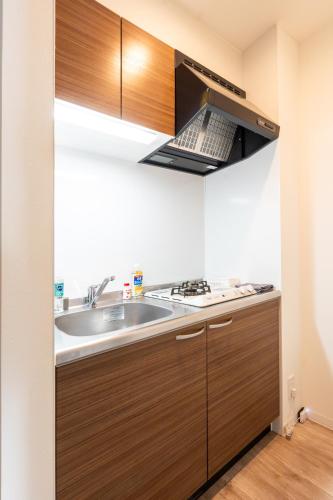 a kitchen with a sink and a stove at Nagomi Apartment Hotel in Hatsukaichi