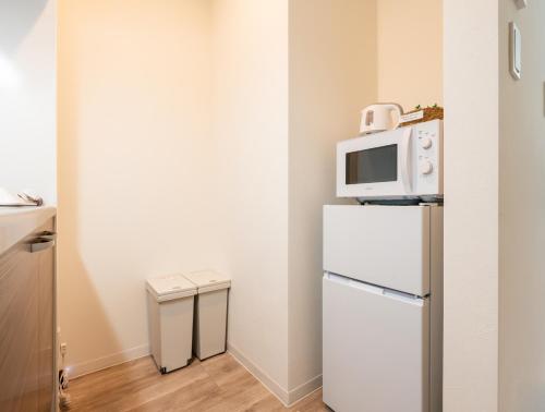 a small kitchen with a microwave on top of a refrigerator at Nagomi Apartment Hotel in Hatsukaichi