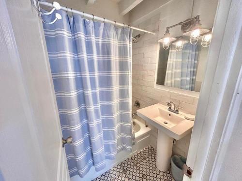 a bathroom with a blue shower curtain and a sink at Baked Beach Bungalow in St. George Island