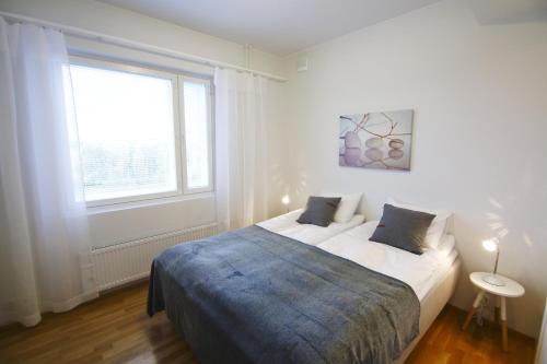 ein weißes Schlafzimmer mit einem großen Bett und einem Fenster in der Unterkunft Northern Lights Apartment in Rovaniemi