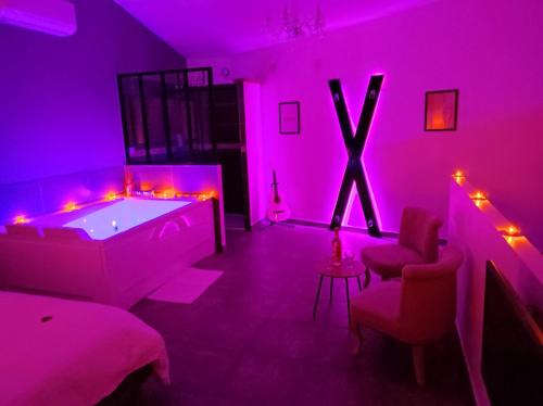 a living room with a tub and pink lighting at La chambre des tentations , love room avec jacuzzi in Bages