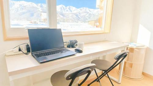 a laptop computer sitting on a desk next to a window at Snow Fever - Clique in Hakuba
