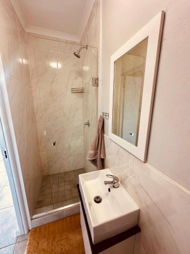 a white bathroom with a sink and a shower at Table Mountain View Apartment II in Cape Town