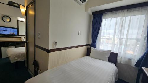 a small room with a bed and a window at Toyoko Inn Tokyo Akigawa-eki Kita-guchi in Akiruno