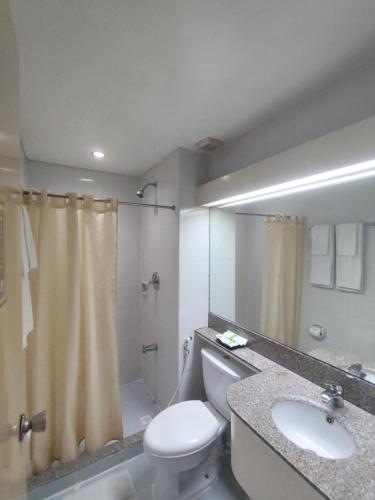 a bathroom with a toilet and a sink and a shower at Albergo Hotel in Baguio