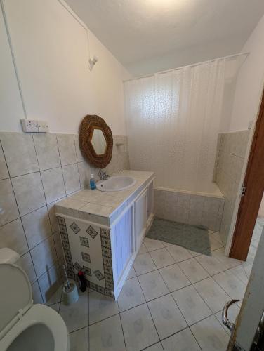 a bathroom with a sink and a toilet and a tub at Desirella Villa APARTMENT in Mahébourg