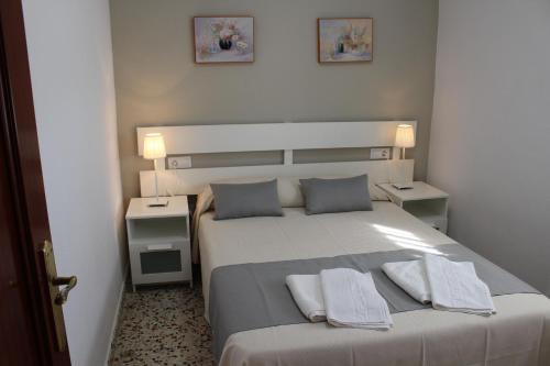 a bedroom with a white bed with two night stands at Apartamentos Bolonia Paraiso in Bolonia