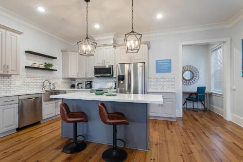 a kitchen with white cabinets and a large island with bar stools at Stunning 4BR-5BR near French Quarter Homes by Hosteeva in New Orleans
