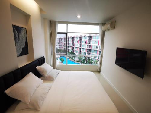 a bedroom with a large white bed and a window at Pattaya Pool View Condo in Nong Prue