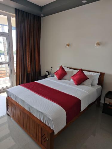 a bedroom with a large bed with red pillows at Lake Star Beach Resort in Kappil