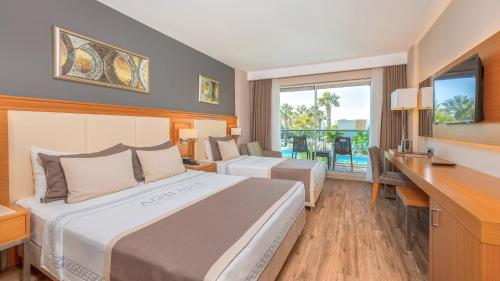 a hotel room with two beds and a desk at Aquasis De Luxe Resort & SPA - Ultra All Inclusive in Didim