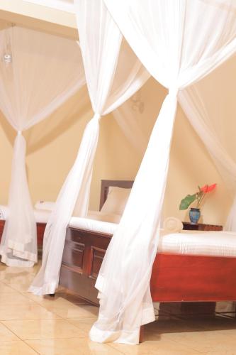 two beds in a room with white drapes at HOIMA KOLPING HOTEL in Hoima