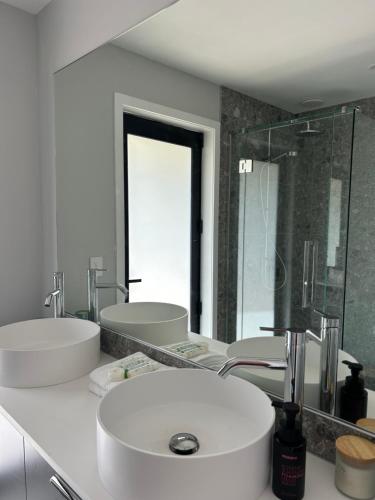 a white bathroom with two sinks and a mirror at Kauri Cabins Tranquil Retreat in Whitianga