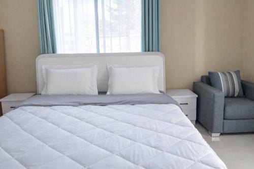 a bedroom with a large white bed and a chair at Milestone Terrace - Premium Apartment near Airport & Super U in Antananarivo
