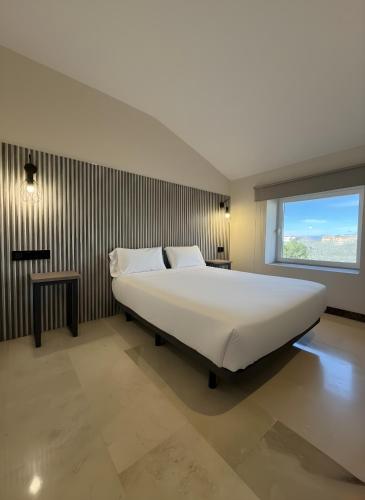 a bedroom with a large bed and a window at Hotel Ciudad de Navalcarnero in Navalcarnero
