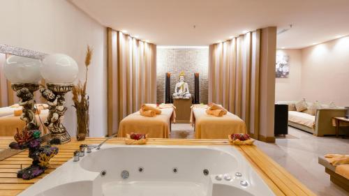 a hotel room with a bath tub and two beds at Aquasis De Luxe Resort & SPA - Ultra All Inclusive in Didim