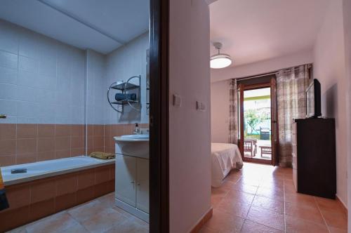 a bathroom with a tub and a sink and a bed at Costa Esuri in Ayamonte