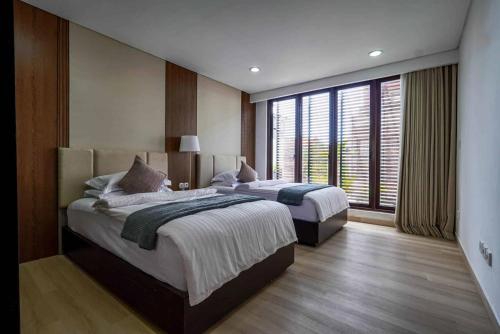 a bedroom with two beds and a large window at Norm Villa Kuta in Kuta
