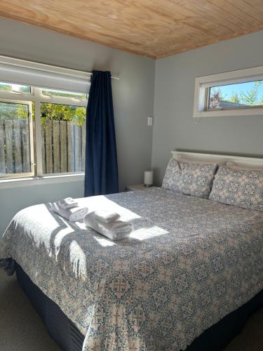 a bedroom with a bed and two windows at A Gem by the Beach 4 bedroom Abel Tasman in Kaiteriteri