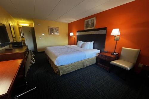 a hotel room with a large bed and a chair at TraveIodge by Wyndham Parsippany in Parsippany