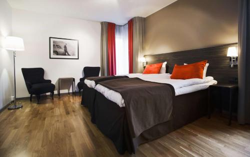 a hotel room with a large bed with orange pillows at Scandic Karlstad City in Karlstad