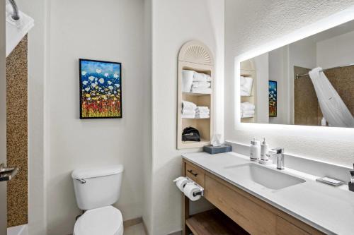 a bathroom with a sink and a toilet and a mirror at La Quinta by Wyndham Searcy in Searcy