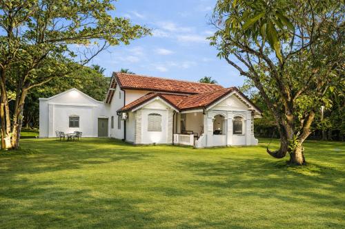 a white house with a green yard with trees at Indigaslanda Walawwa in Bopitiya