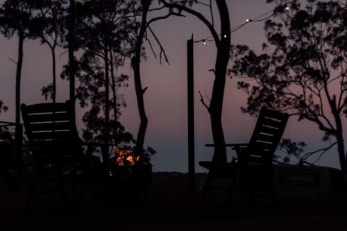 a group of chairs sitting next to trees at night at Tiny Tamborine 2 by Tiny Away in Wongawallan