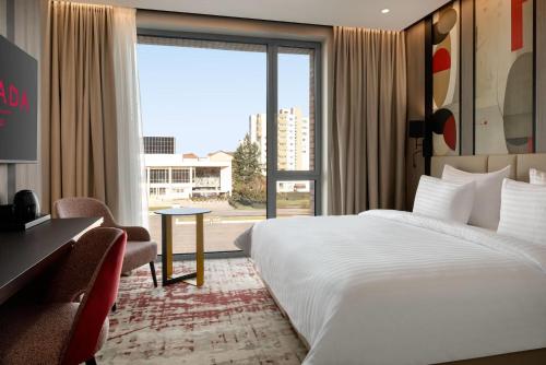 a hotel room with a bed and a desk and a window at Ramada by Wyndham Zalau in Zalău