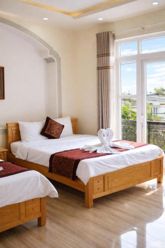 two beds in a room with a window at Kim Ngân Hotel Buôn Ma Thuột in Buon Ma Thuot