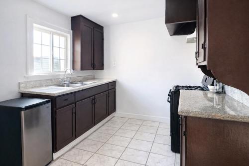 a kitchen with brown cabinets and a sink and a window at Vernon Homes For The Soul in Los Angeles