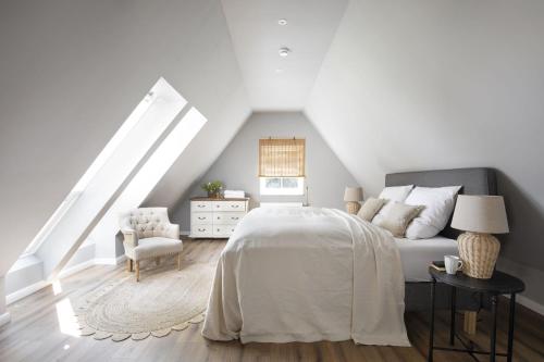 a white bedroom with a bed and a chair at Fischerkate - Ostholstein in Stocksee