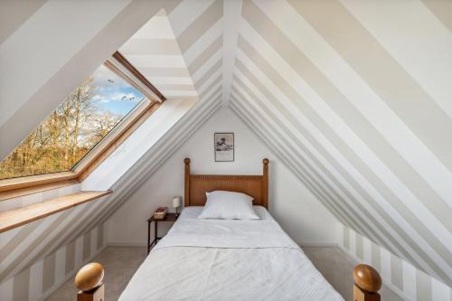 a attic bedroom with a bed and a window at Landhaus Köhn - Ostholstein in Giekau