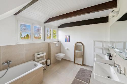 a bathroom with a tub and a toilet and a sink at Landhaus Köhn - Ostholstein in Giekau
