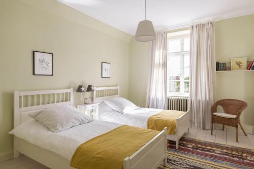 a bedroom with two beds and a chair and a window at Pächterhaus - Ostholstein in Manhagen