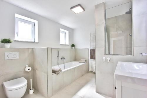 a bathroom with a toilet and a tub and a sink at Ferienhaus Schreieck in Pöcking