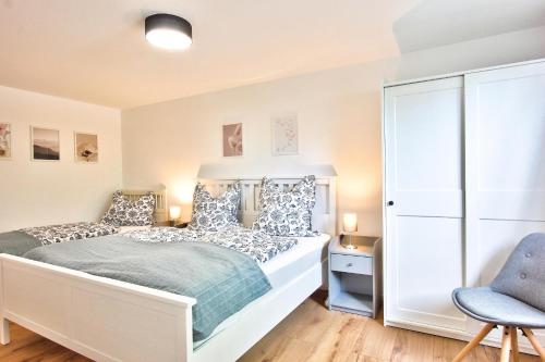 a bedroom with a white bed and a blue chair at Ferienhaus Schreieck in Pöcking
