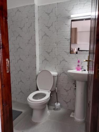 a bathroom with a white toilet and a sink at Relax Crib Nairobi in Nairobi