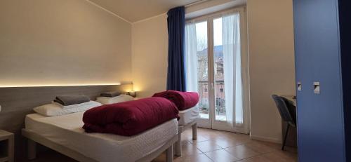 a bedroom with a bed with a red blanket on it at Ostello Città di Rovereto in Rovereto