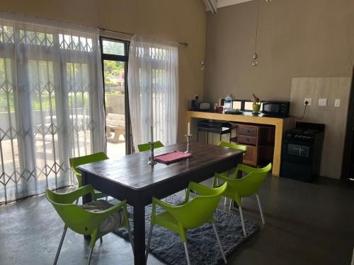 a kitchen with a wooden table and green chairs at Rapids View Cottage in Parys