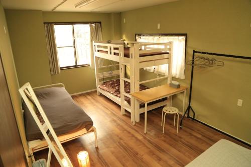 a room with a bunk bed and a desk and a bed at Bonfire Hostel Osaka in Osaka