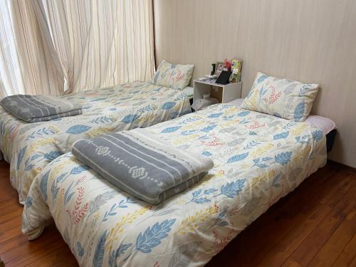 two beds sitting next to each other in a bedroom at Kami House in Amami